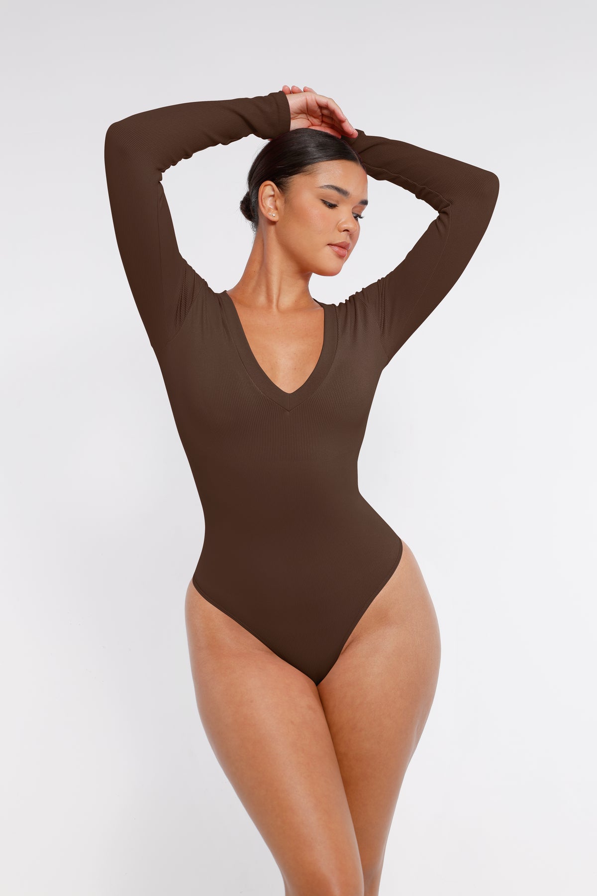 Long Sleeve Ribbed V Neck Bodysuit in brown – model posing with arms raised